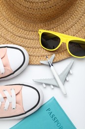 Photo of Time for summer vacation. Toy plane, passport, shoes and beach accessories on white background, flat lay