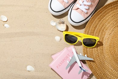 Photo of Time for summer vacation. Toy plane, passports, shoes and beach accessories on sand, flat lay. Space for text