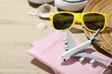 Photo of Time for summer vacation. Toy plane, passports and beach accessories on sand, closeup. Space for text