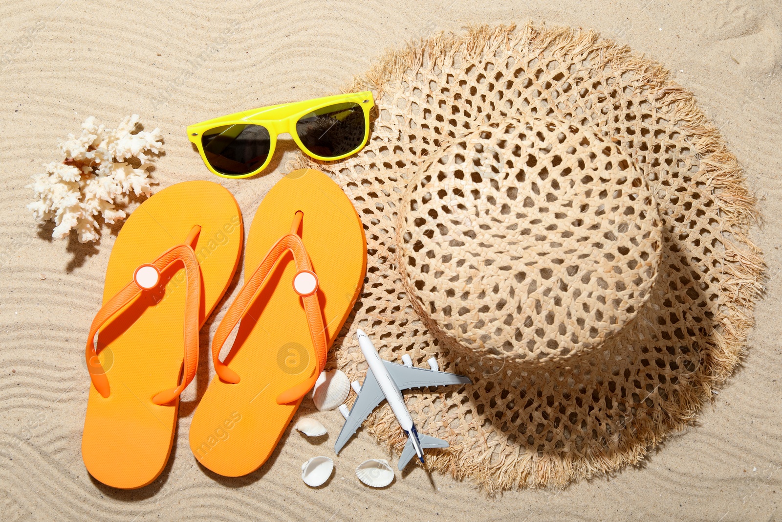 Photo of Time for summer vacation. Beach accessories and toy plane on sand, flat lay
