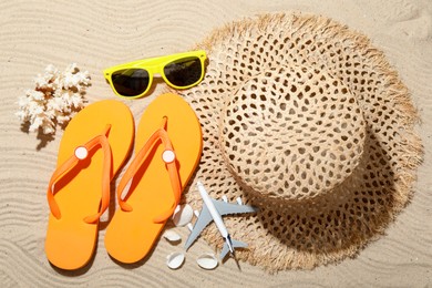 Photo of Time for summer vacation. Beach accessories and toy plane on sand, flat lay
