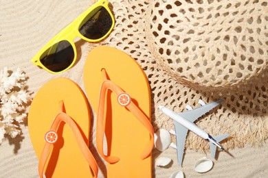 Photo of Time for summer vacation. Beach accessories and toy plane on sand, flat lay