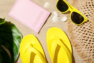Photo of Time for summer vacation. Passport, green leaf and beach accessories on sand, flat lay