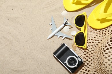 Photo of Time for summer vacation. Camera, toy plane and beach accessories on sand, flat lay. Space for text