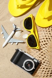 Photo of Time for summer vacation. Camera, toy plane and beach accessories on sand, flat lay