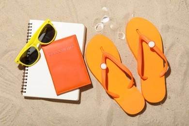 Photo of Time for summer vacation. Passport, notebook and beach accessories on sand, flat lay