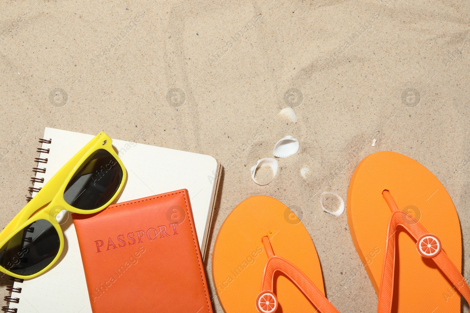 Photo of Time for summer vacation. Passport, notebook and beach accessories on sand, flat lay. Space for text