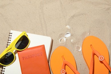 Photo of Time for summer vacation. Passport, notebook and beach accessories on sand, flat lay. Space for text