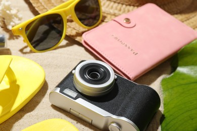 Photo of Time for summer vacation. Camera, passport, green leaf and beach accessories on sand, closeup