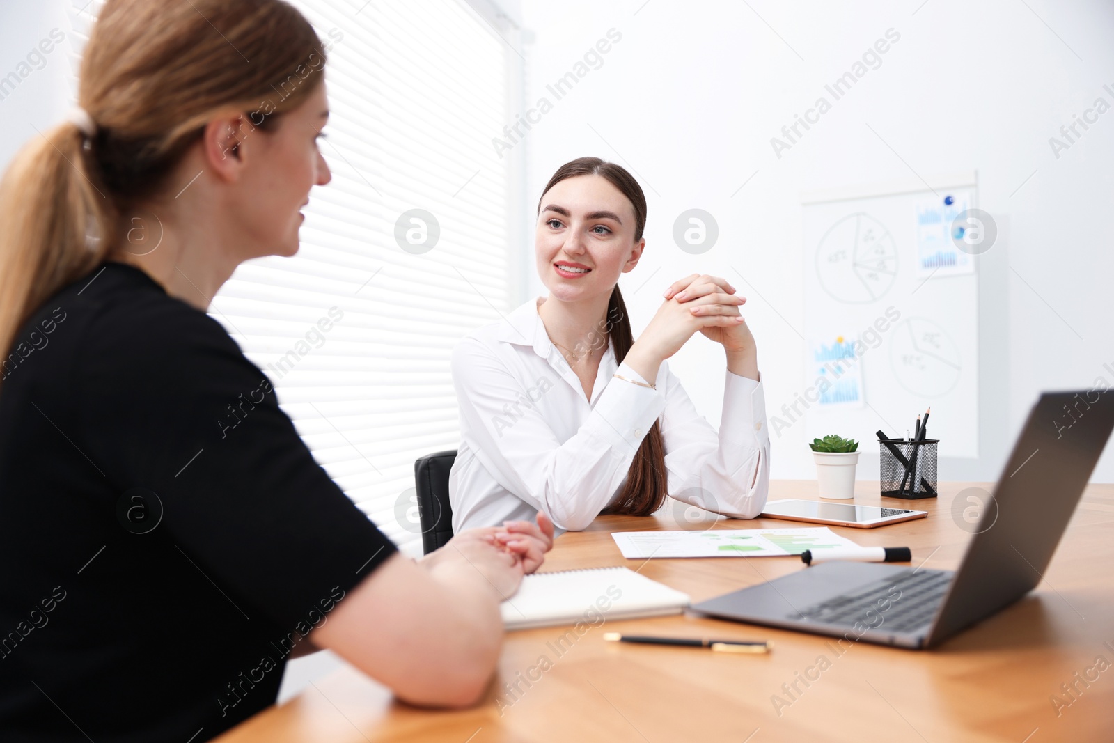 Business coach working with woman at wooden table in office Photo of Business coach working with woman at wooden table in office