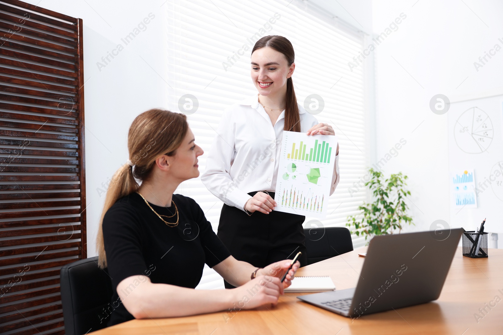 Business coach working with woman at wooden table in office Photo of Business coach working with woman at wooden table in office
