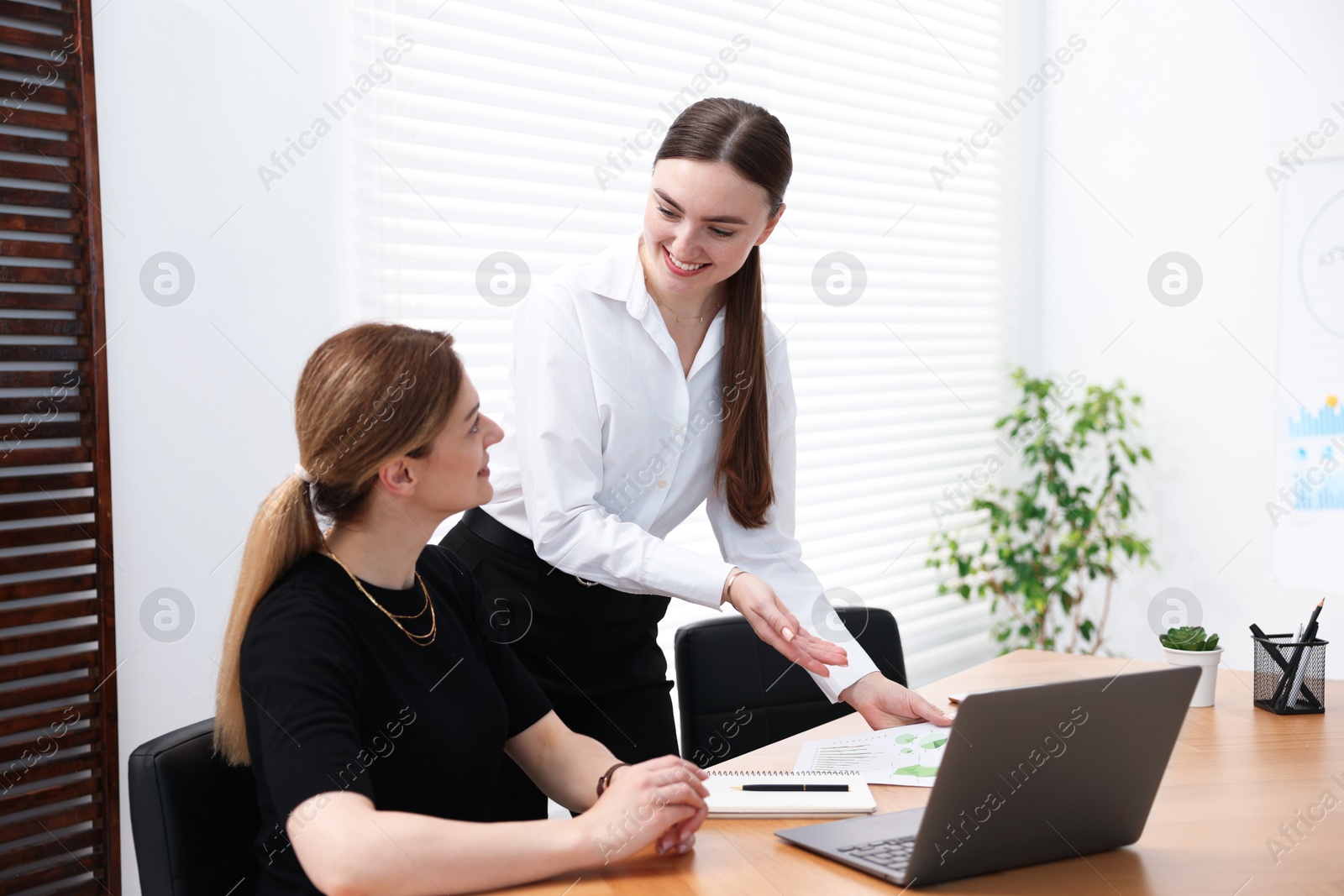 Business coach working with woman at wooden table in office Photo of Business coach working with woman at wooden table in office
