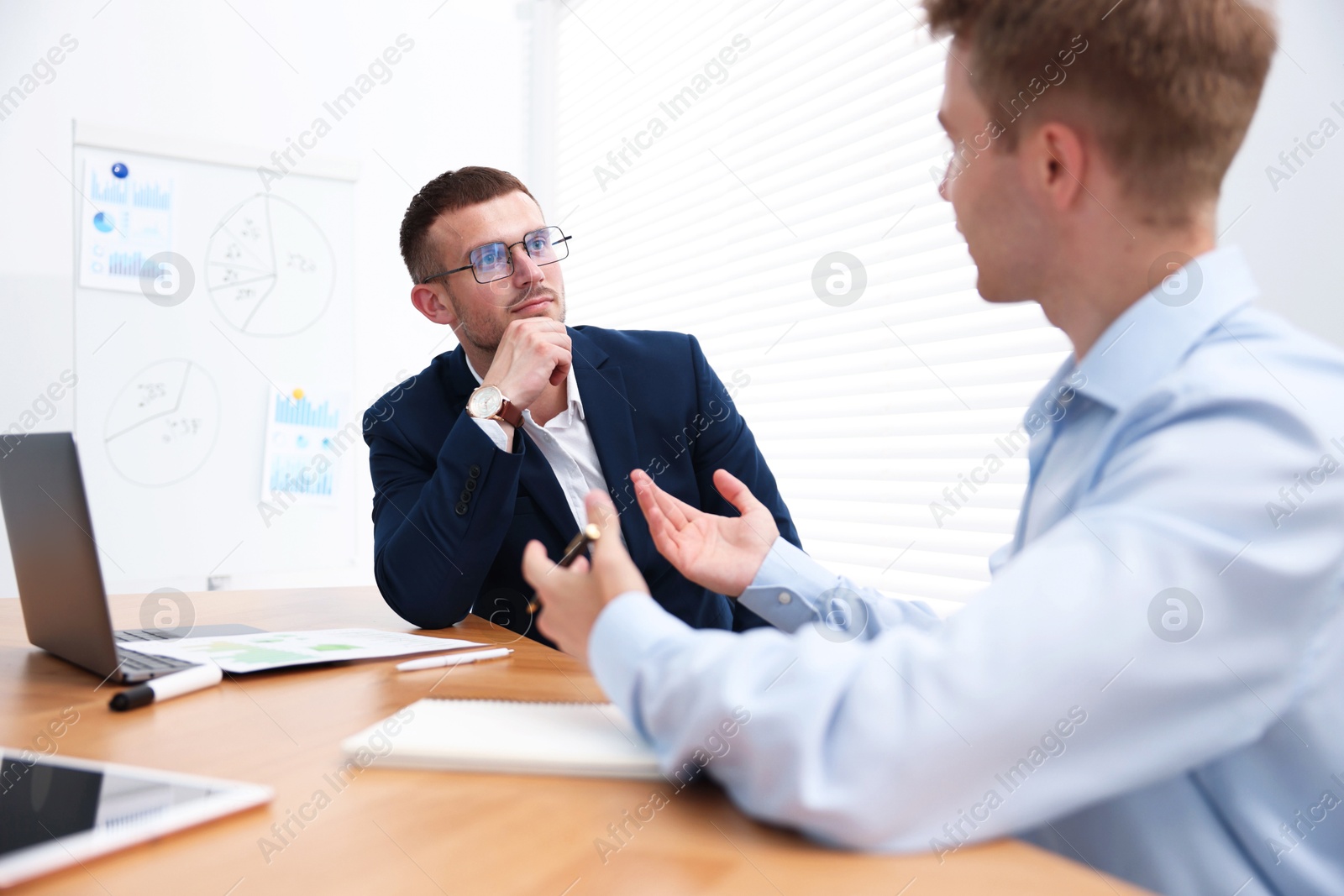 Business coach working with man at wooden table in office Photo of Business coach working with man at wooden table in office