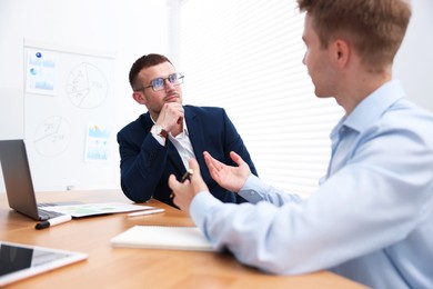 Photo of Business coach working with man at wooden table in office