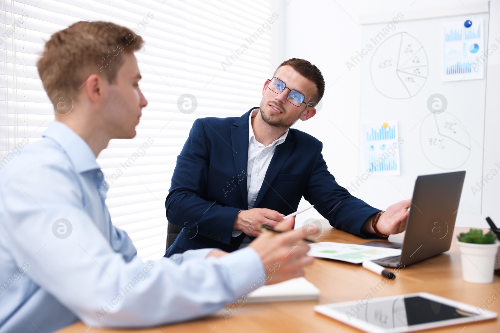 Business coach working with man at wooden table in office Photo of Business coach working with man at wooden table in office