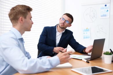 Photo of Business coach working with man at wooden table in office