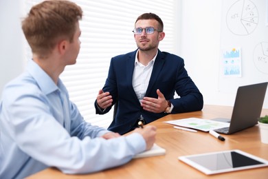 Photo of Business coach working with man at wooden table in office