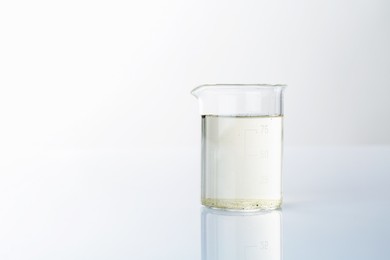 Photo of Glass beaker with dirty water on mirror surface, space for text