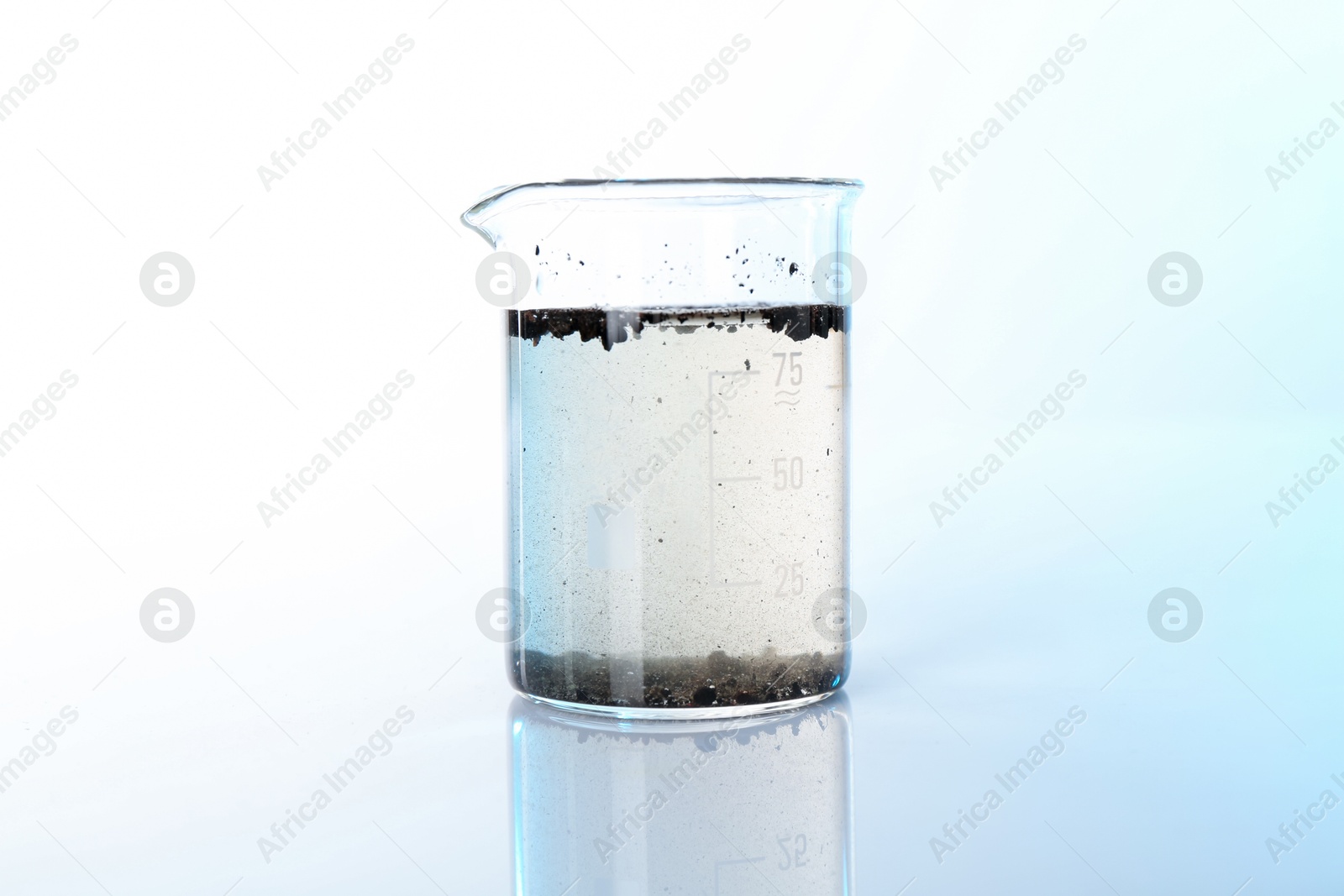 Glass beaker with dirty water on mirror surface Photo of Glass beaker with dirty water on mirror surface