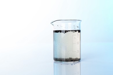 Photo of Glass beaker with dirty water on mirror surface, space for text