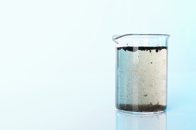 Photo of Glass beaker with dirty water on mirror surface, space for text