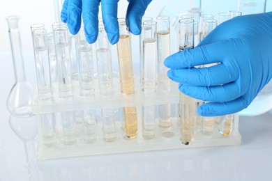 Photo of Examination of water quality. Scientist with test tubes of samples at table against light background, closeup