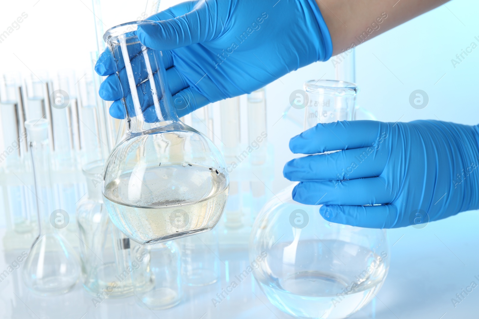 Scientist with flasks of dirty and clean water at table against light background, closeup Photo of Scientist with flasks of dirty and clean water at table against light background, closeup