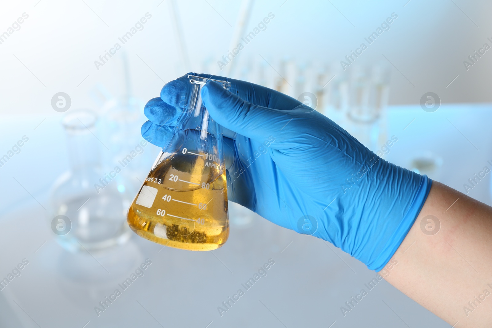 Photo of Scientist holding flask with dirty water against blurred background, closeup