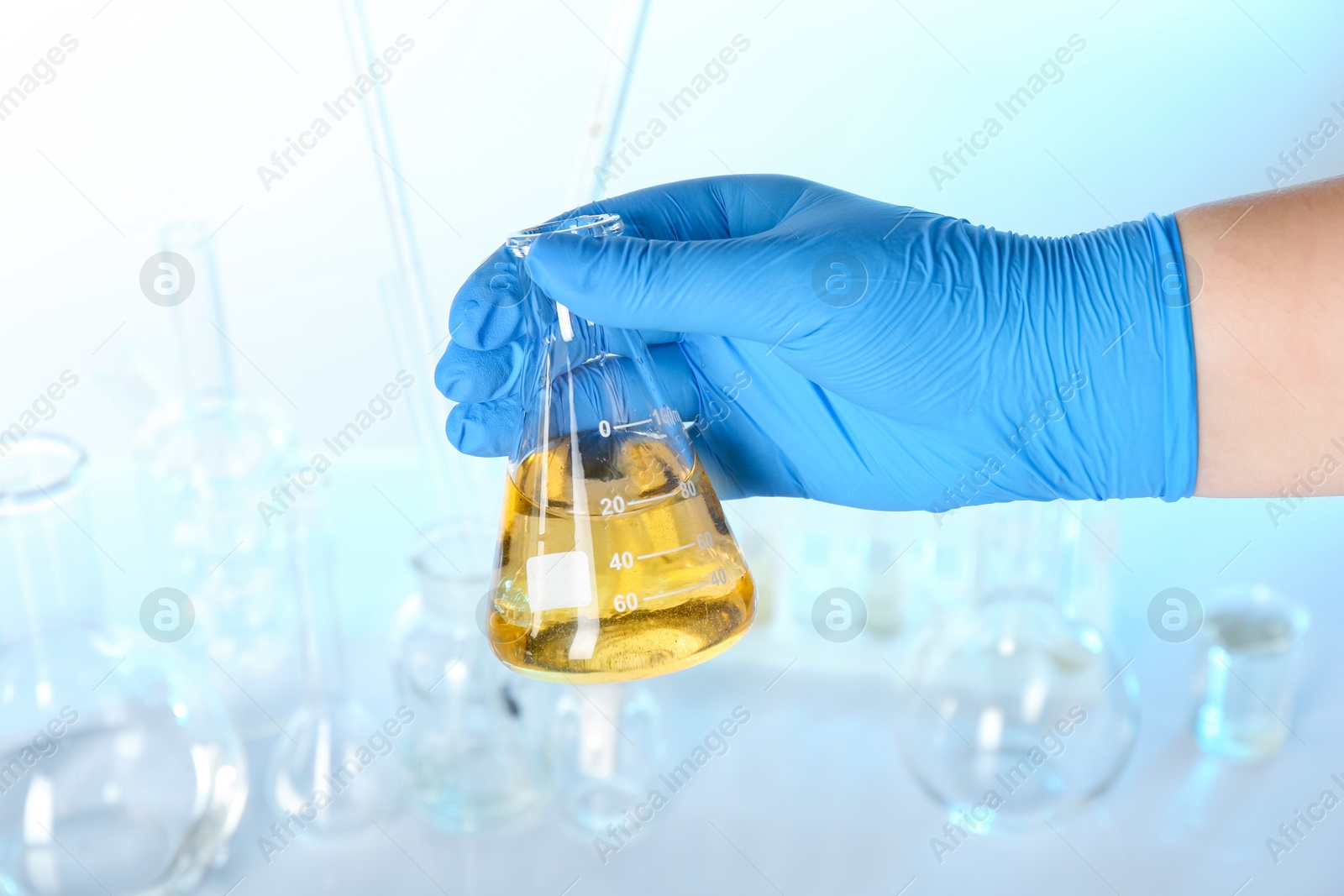 Photo of Scientist holding flask with dirty water against blurred background, closeup