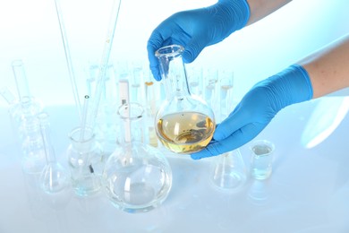 Photo of Scientist with flask of dirty water at table against light background, closeup