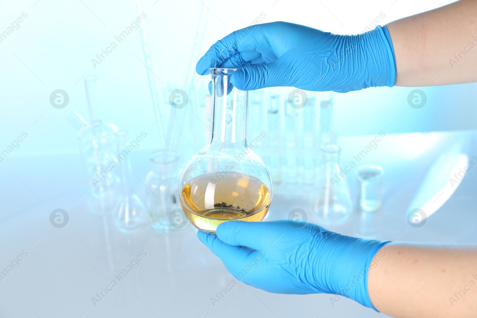 Scientist with flask of dirty water at table against light background, closeup Photo of Scientist with flask of dirty water at table against light background, closeup