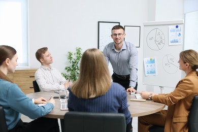 Photo of Business coach giving presentation to group of people in office