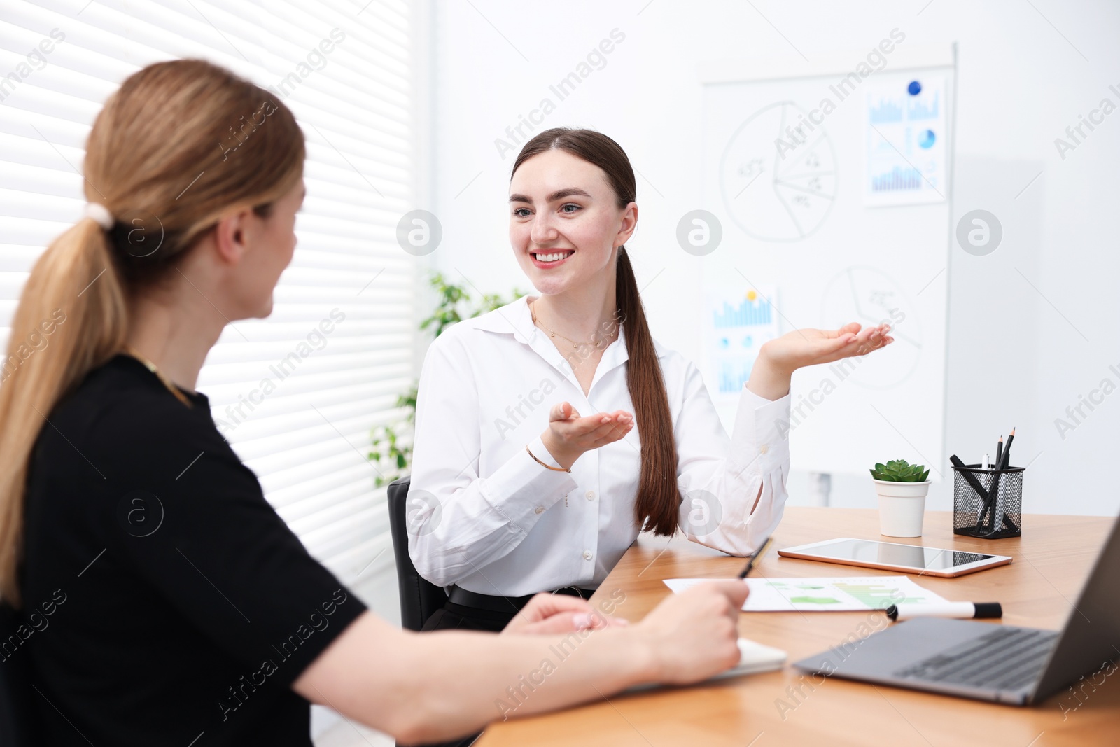 Business coach working with woman at wooden table in office Photo of Business coach working with woman at wooden table in office