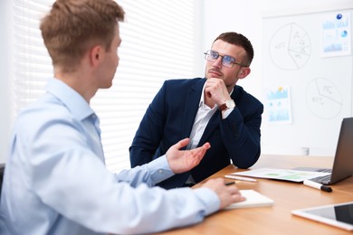 Photo of Business coach working with man at wooden table in office