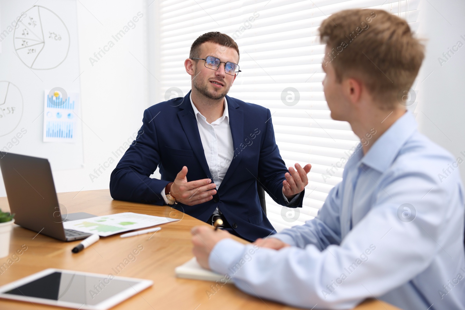 Business coach working with man at wooden table in office Photo of Business coach working with man at wooden table in office