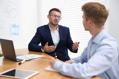 Photo of Business coach working with man at wooden table in office