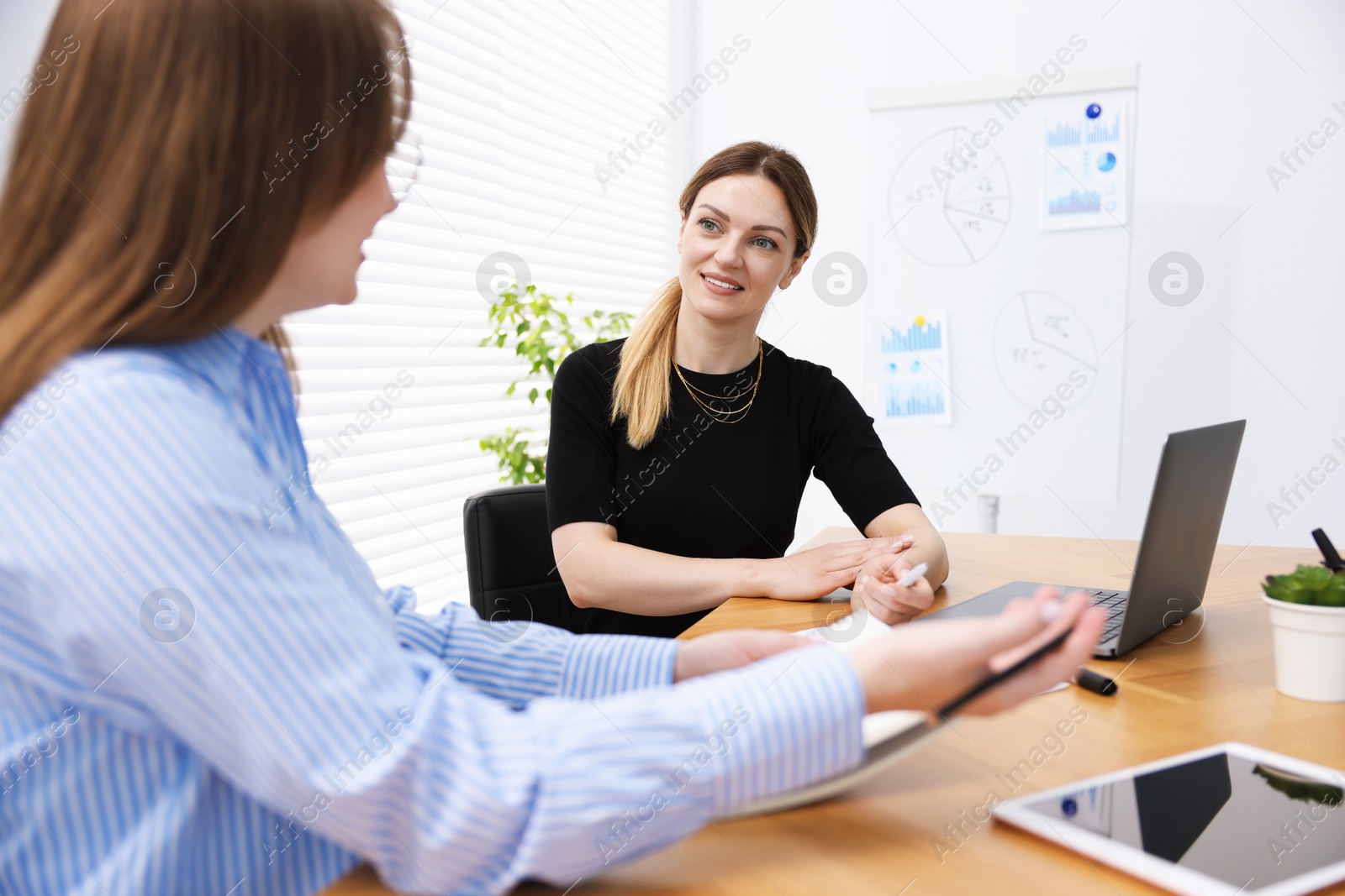 Business coach working with woman at wooden table in office Photo of Business coach working with woman at wooden table in office