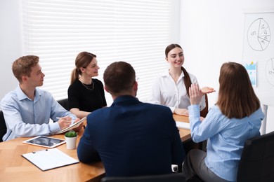 Photo of Business coach giving presentation to group of people in office