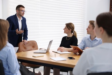 Photo of Business coach working with group of people in office