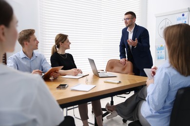 Photo of Business coach giving presentation to group of people in office