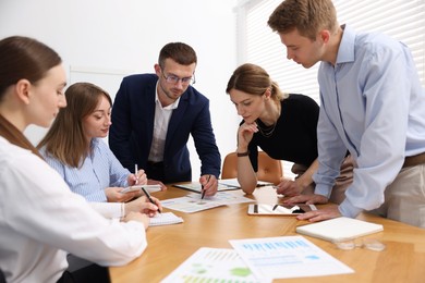 Photo of Business coach working with group of people in office