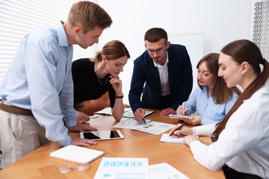 Photo of Business coach working with group of people in office