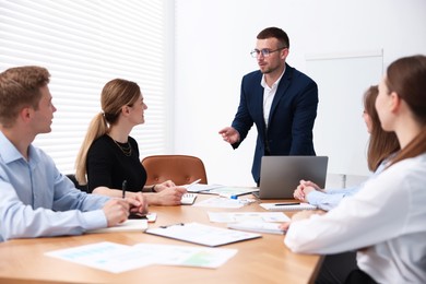 Photo of Business coach giving presentation to group of people in office