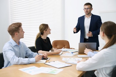 Photo of Business coach giving presentation to group of people in office