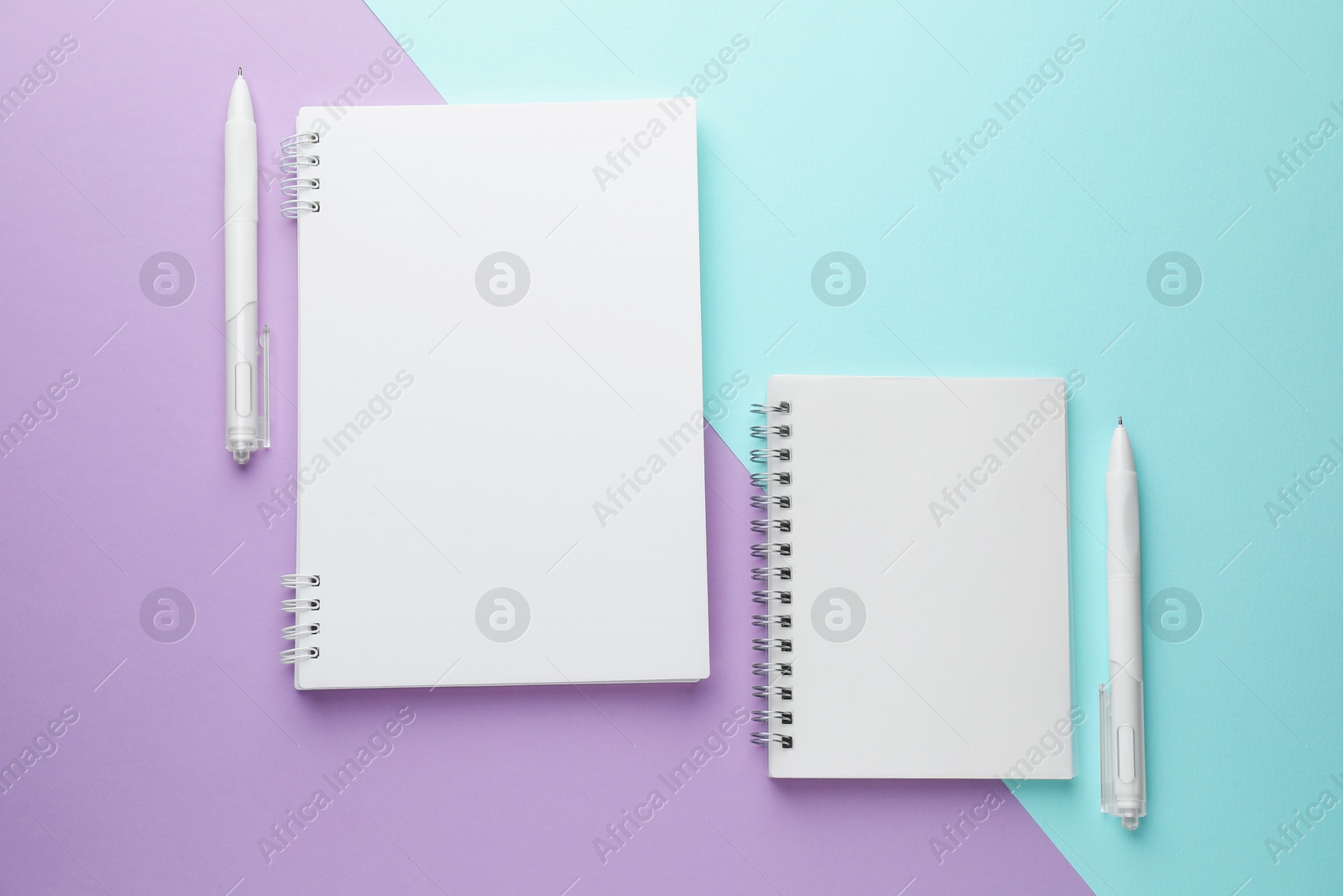 White notebooks and pens on color background, flat lay Photo of White notebooks and pens on color background, flat lay