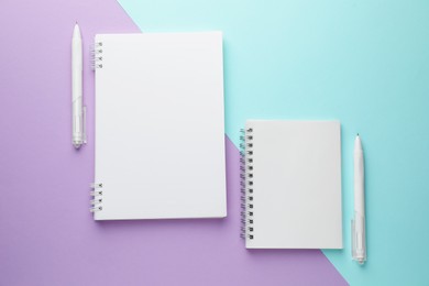 Photo of White notebooks and pens on color background, flat lay