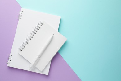 Photo of White notebooks and pen on color background, top view. Space for text