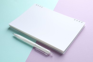 Photo of White notebook and pen on color background, closeup