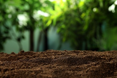Photo of Fertile soil against blurred green background, closeup. Space for text