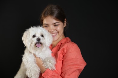 Photo of Happy teenage girl with Maltese dog on black background